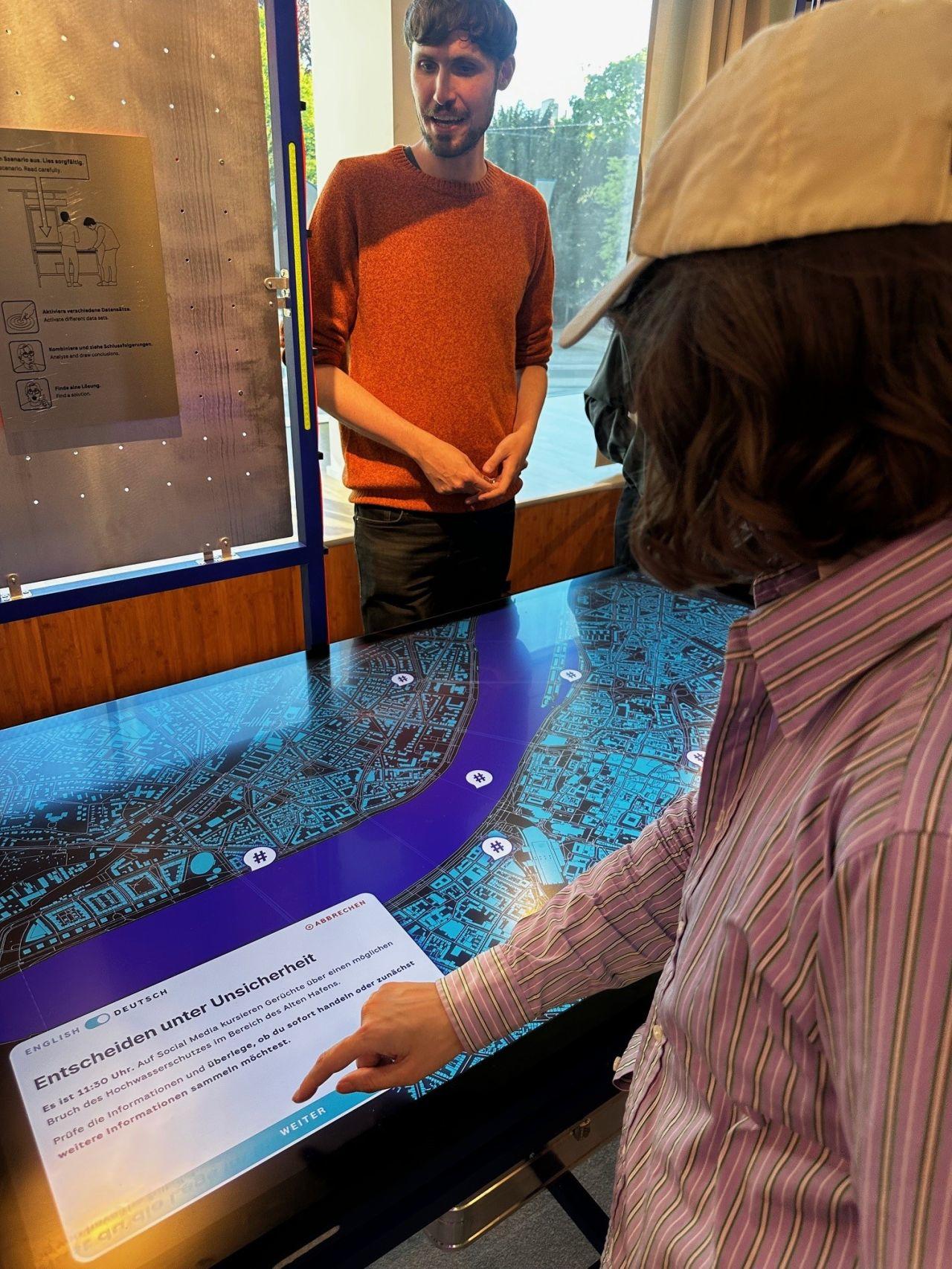 Interaktive Station der Ausstellung mit Touchscreen-Szenario „Entscheiden unter Unsicherheit"