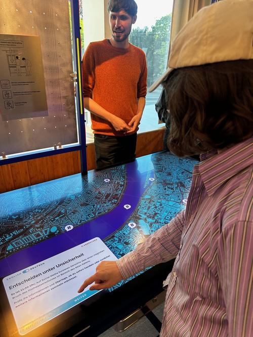 Interaktive Station der Ausstellung mit Touchscreen-Szenario „Entscheiden unter Unsicherheit"